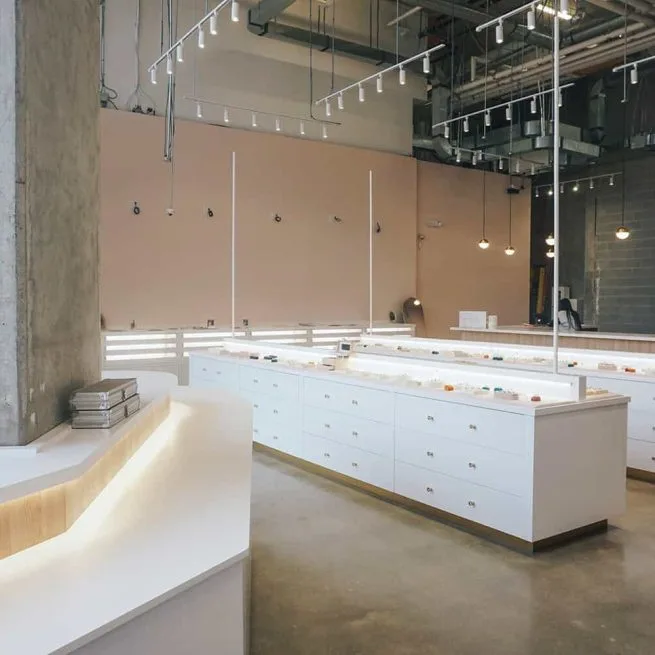 White display cabinets under track lighting in Engage Studio's industrial-style Toronto showroom