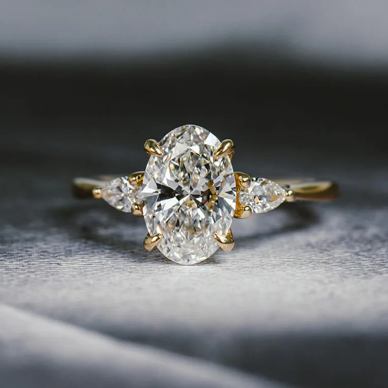 Oval and pear three-stone engagement ring: an oval diamond between two pear-cut diamonds in yellow gold
