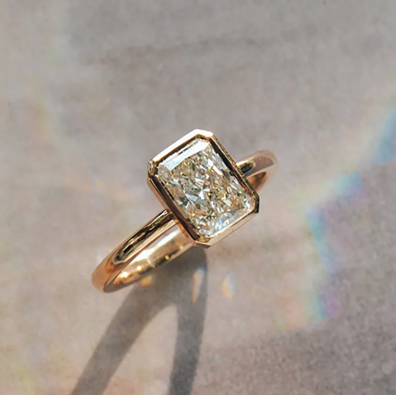 Radiant bezel engagement ring in rose gold: a radiant-cut diamond in a bezel on a slim band