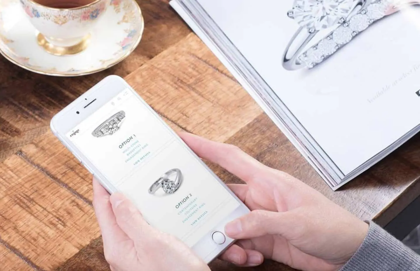 Hands holding a phone open on ring design options, the first-step band background
