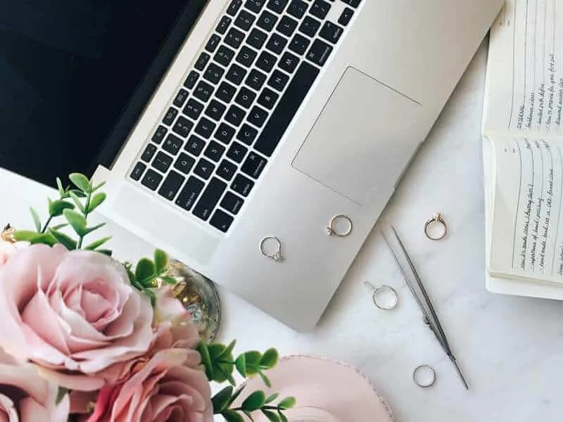 Rose, laptop keyboard and a ring box on a white desk, the lead-form background