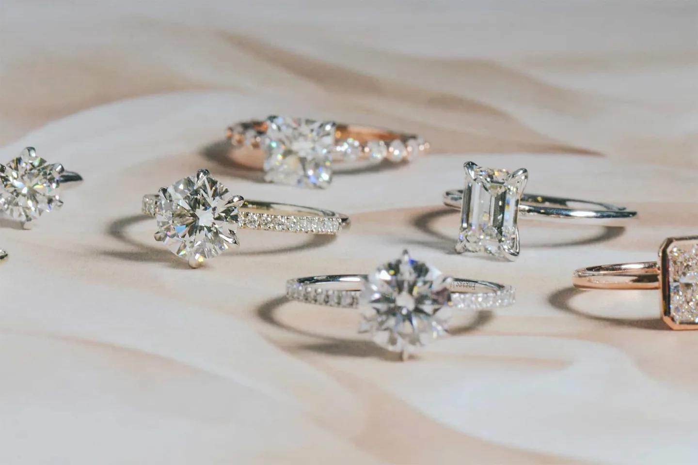 Row of diamond engagement rings in gold and white gold on a cream background