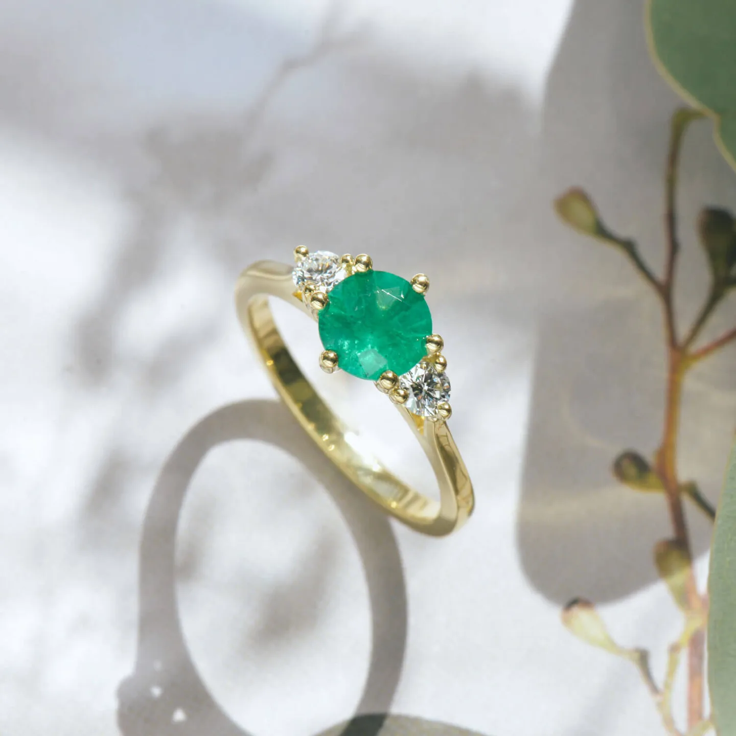 Round green emerald engagement ring in 18k yellow gold with diamond side stones