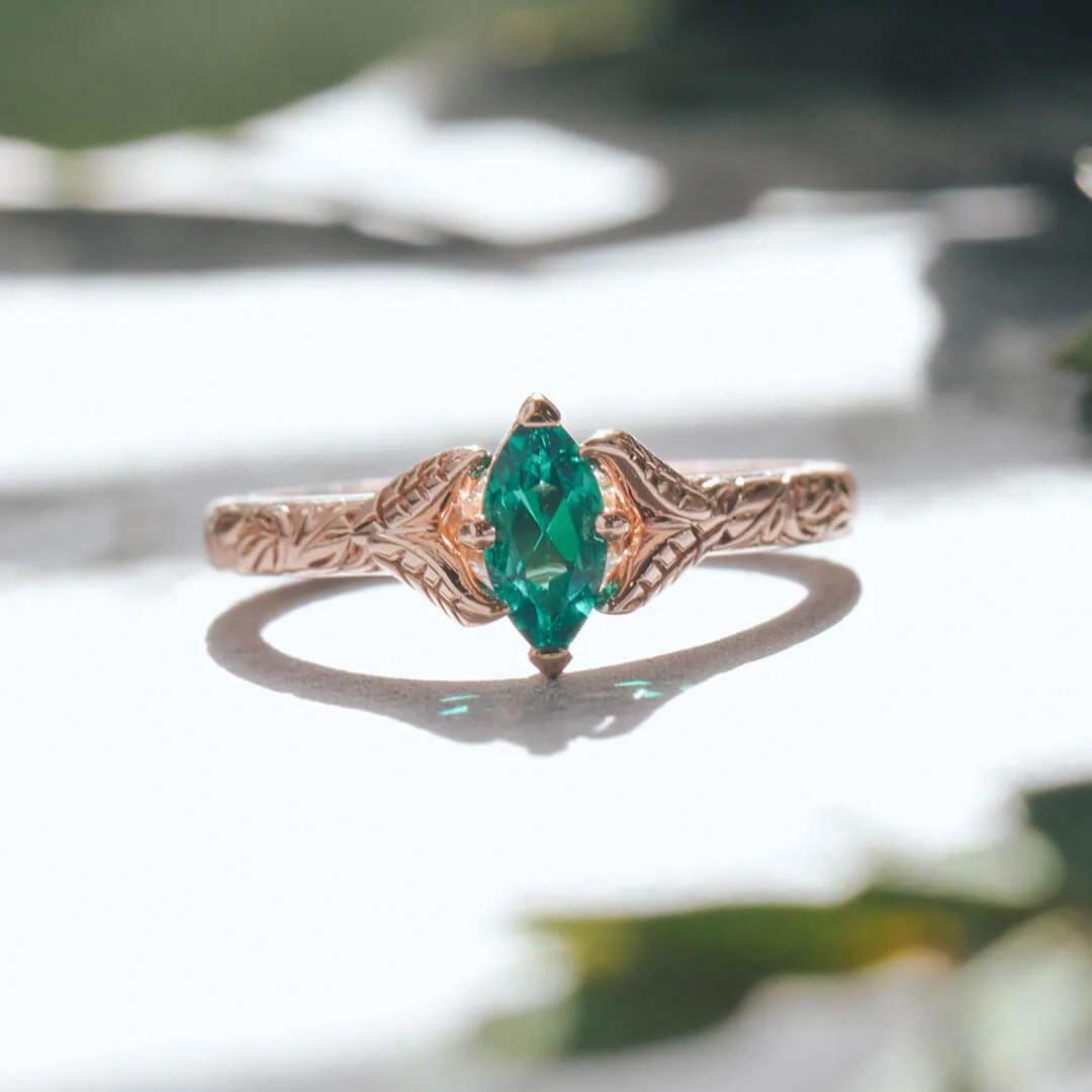 Marquise green emerald engagement ring in rose gold with a vintage-inspired band