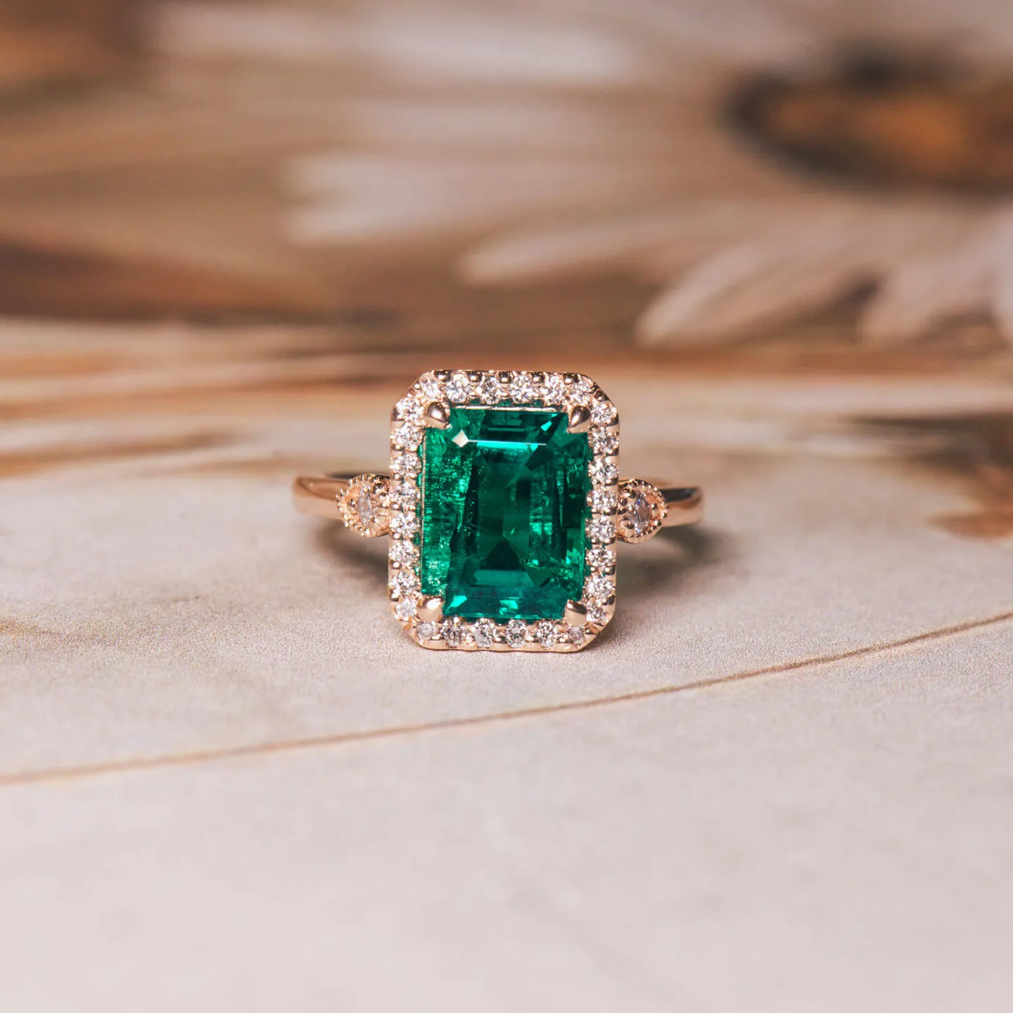 Emerald-cut green emerald halo engagement ring in rose gold with a diamond band