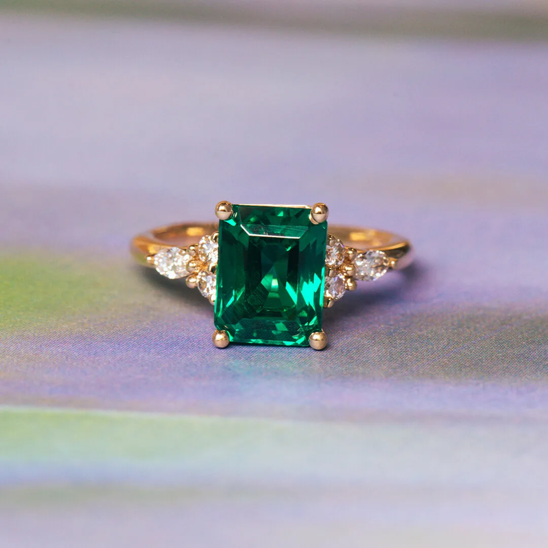 Emerald-cut green emerald engagement ring in yellow gold with diamond accents