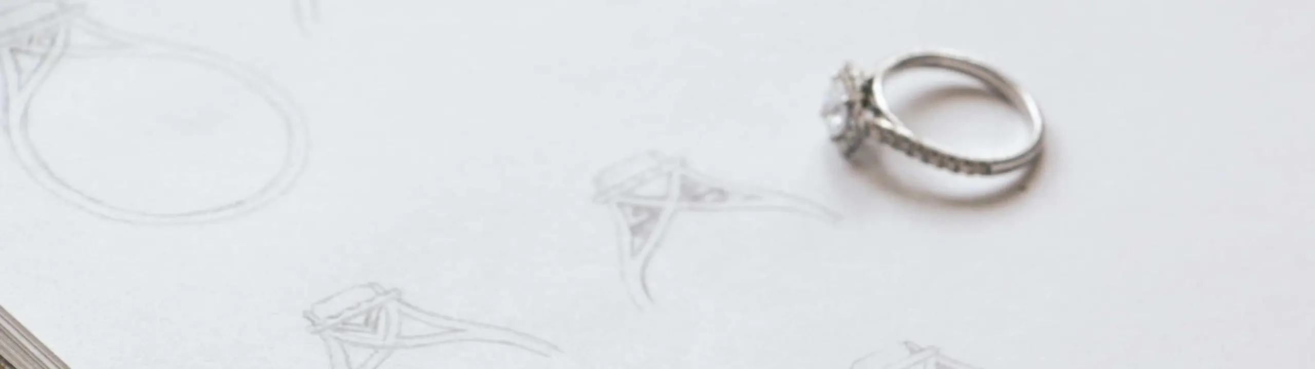 Pencil sketches of engagement ring designs on a notepad