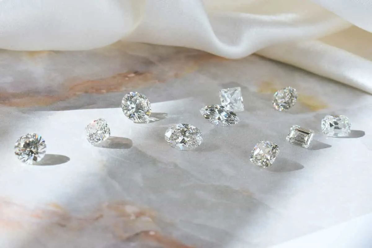 Loose diamonds in different shapes scattered on a pale marble surface