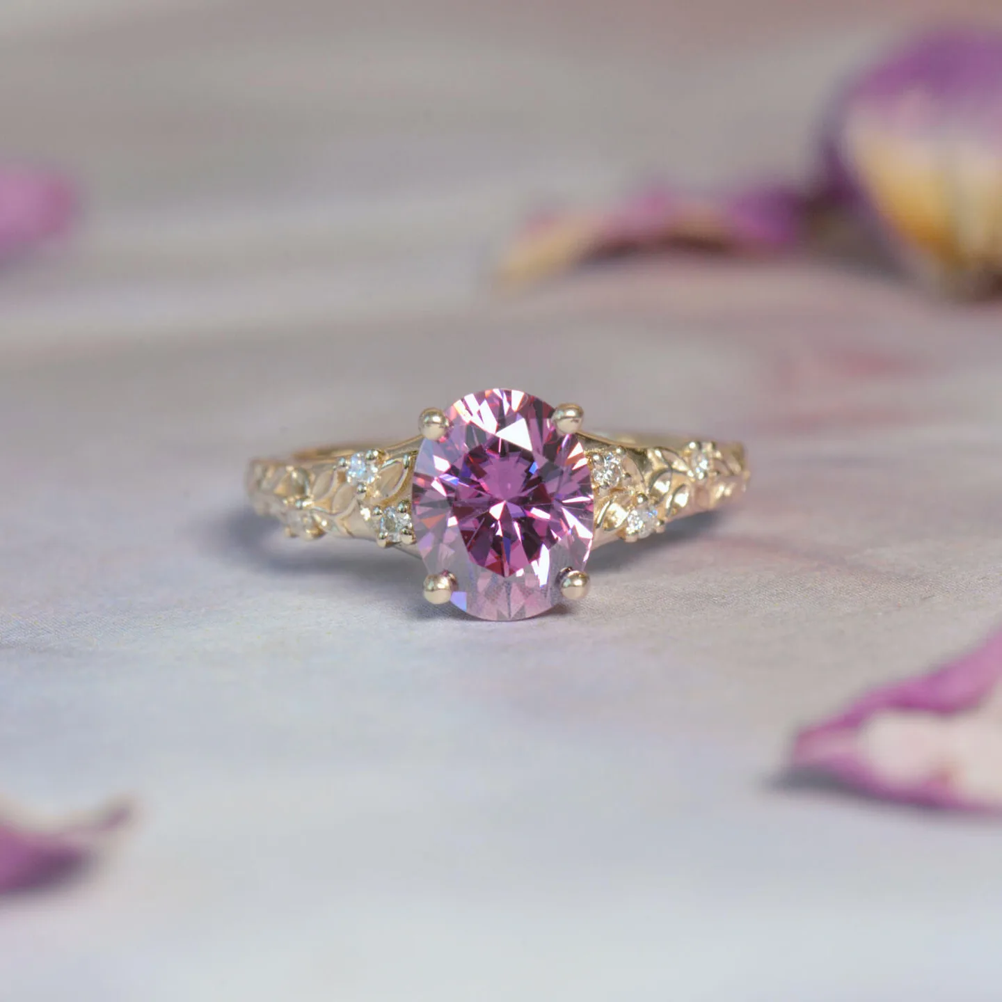 Oval pink gemstone engagement ring in yellow gold with a pave band on rose petals