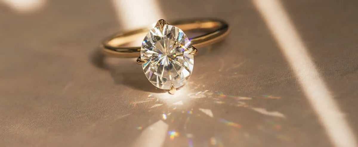 Sunlit rainbow sparkle thrown across a wooden table by an engagement ring