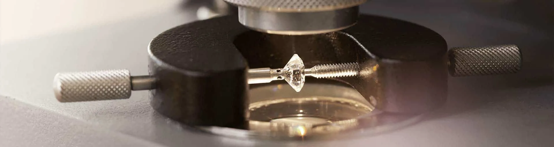 A diamond held in the stone clamp of a gem microscope, close up