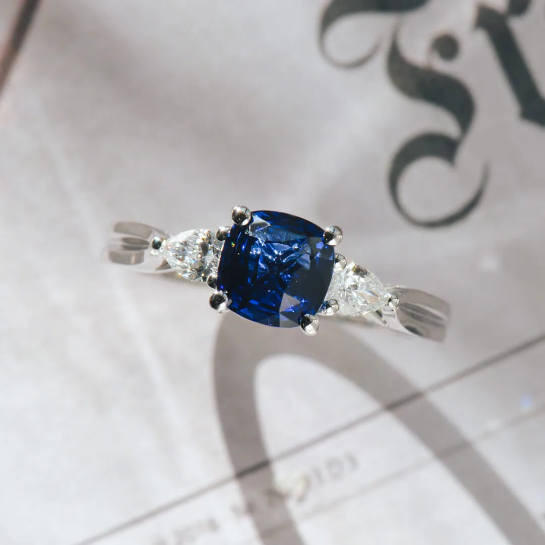 Cushion three-stone blue sapphire engagement ring in white gold with pear diamond sides