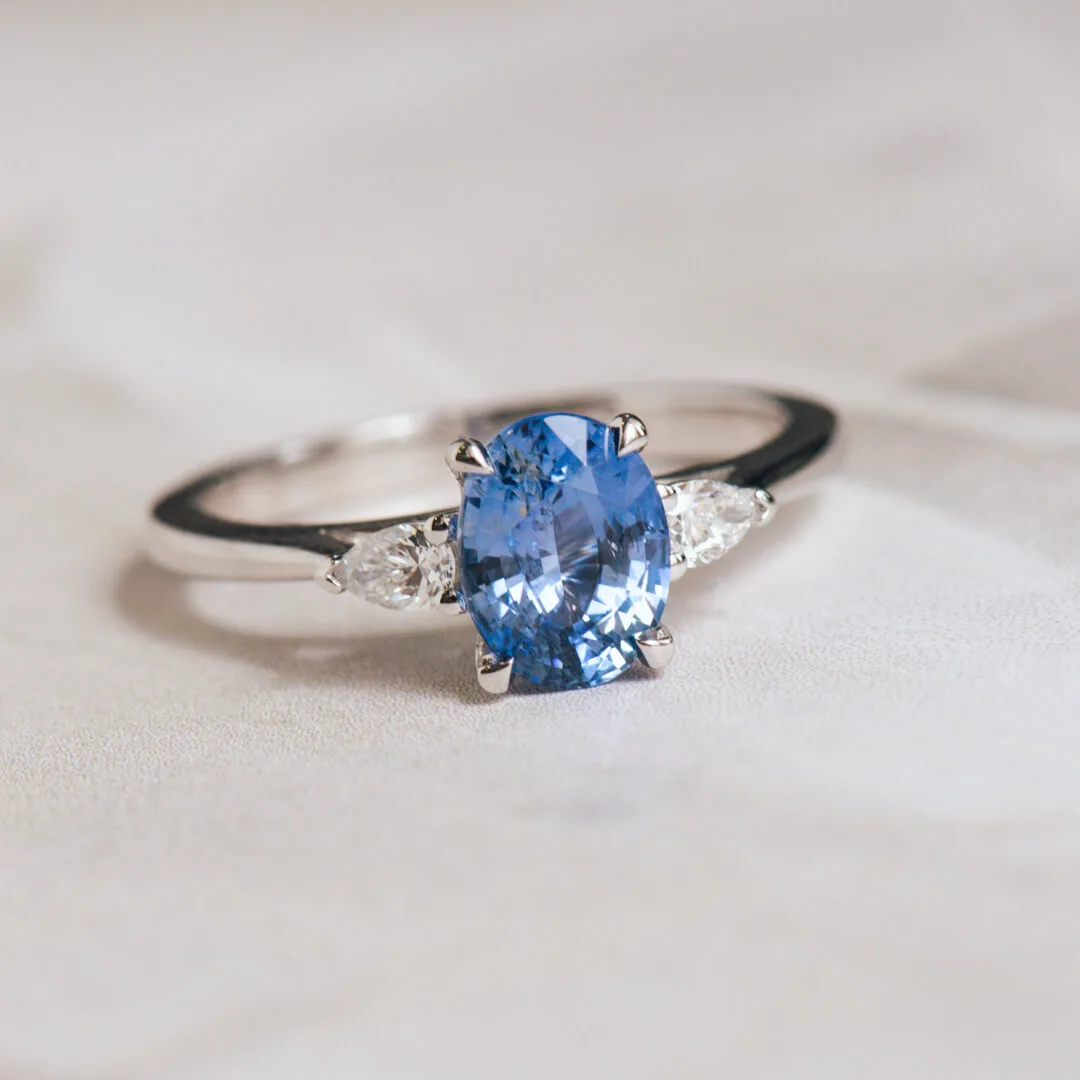 Oval blue sapphire three-stone ring in white gold with pear diamond sides
