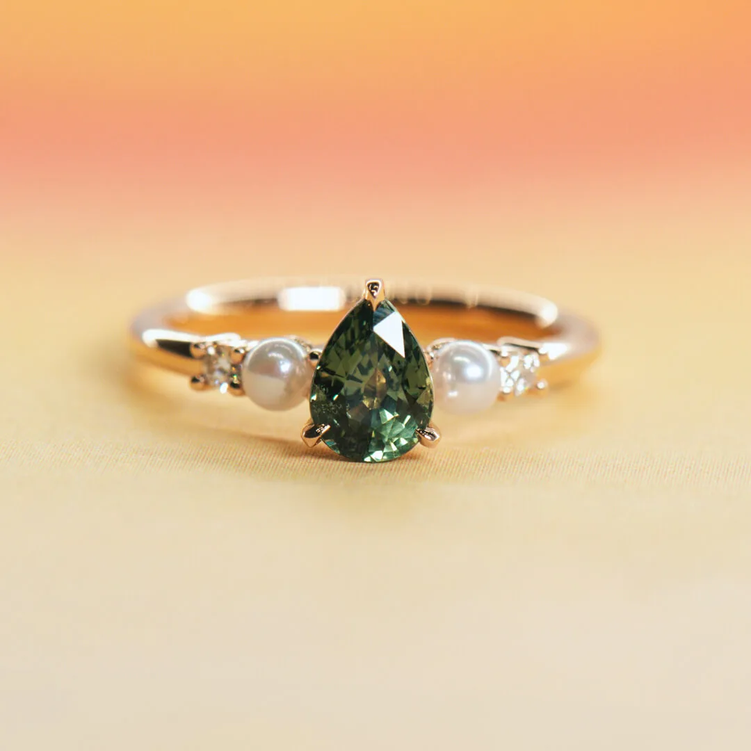 Green sapphire and pearl engagement ring in yellow gold with a pear-cut centre stone