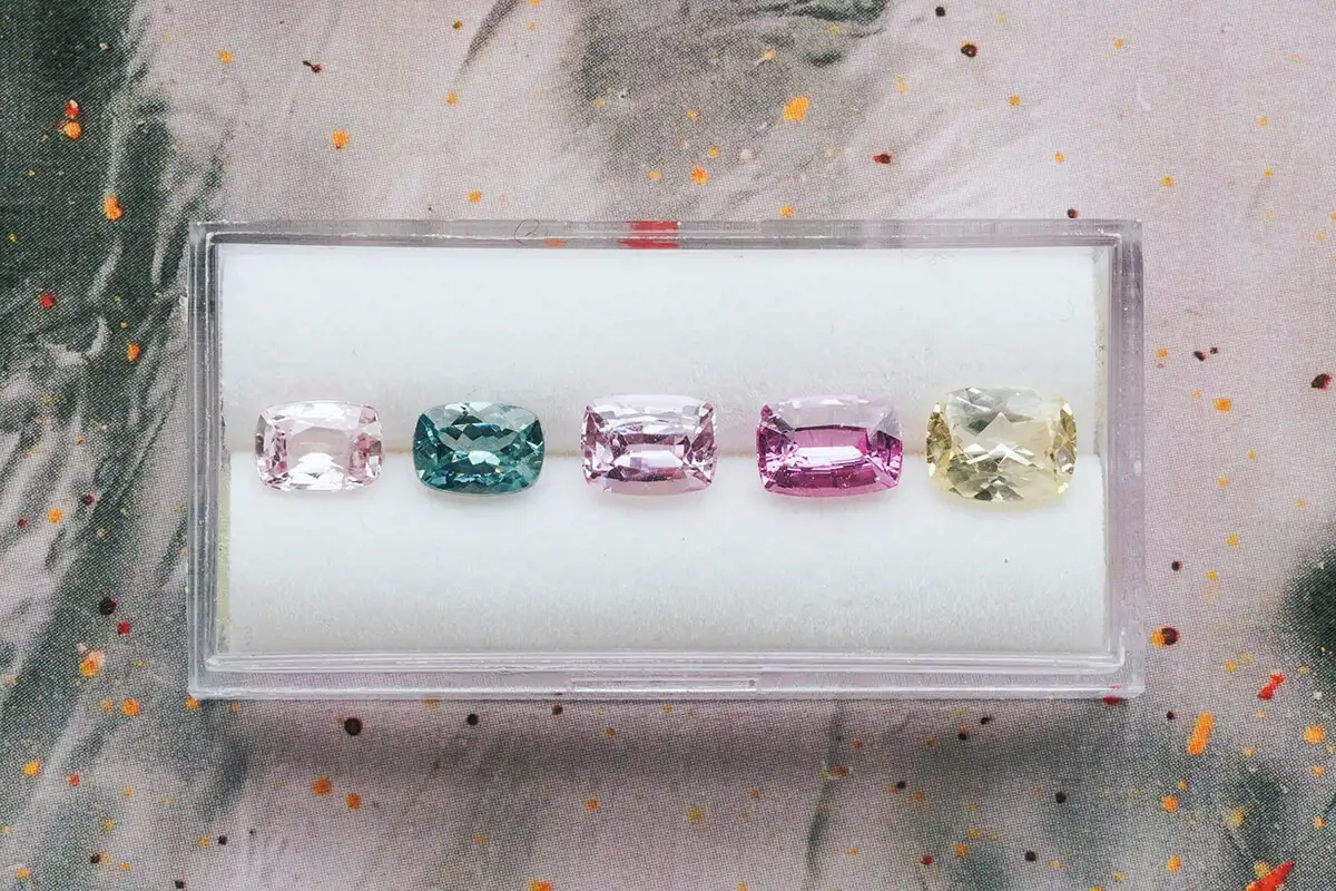 Elongated cushion sapphires in padparadscha, teal, pink, magenta and yellow in a white tray