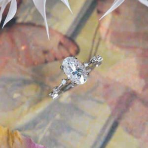 Oval moissanite engagement ring on 14k white gold featuring smaller stones spread apart on the sides.