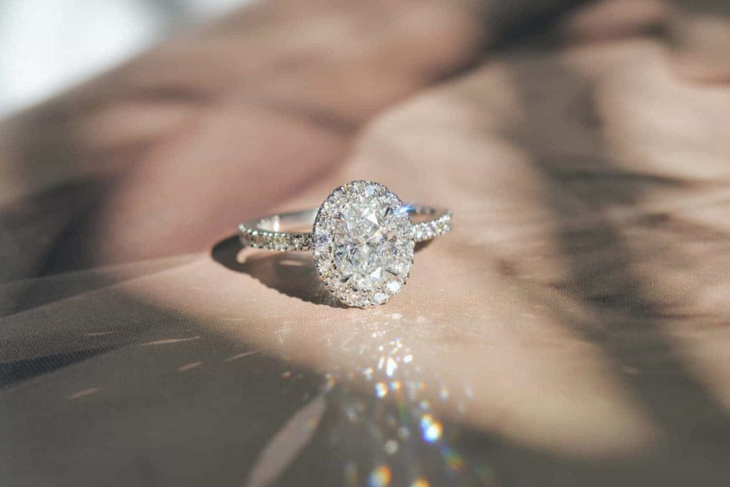 White gold, oval cut engagement ring with natural round diamonds in a halo